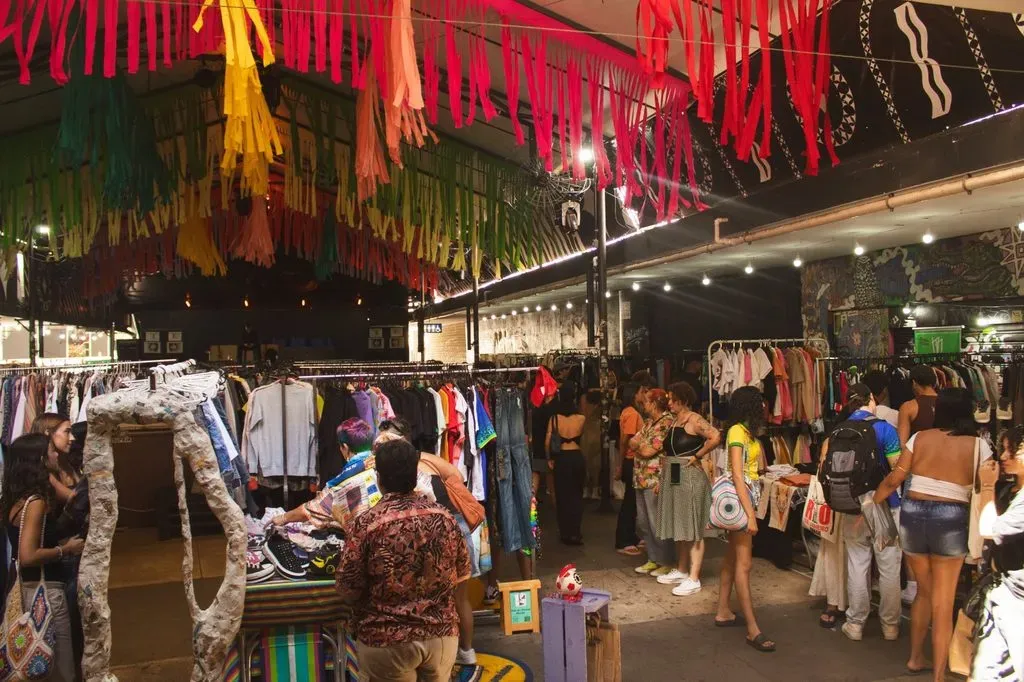 Visitantes entre araras de roupas em edição anterior do brechó Ao Desapego (Divulgação)