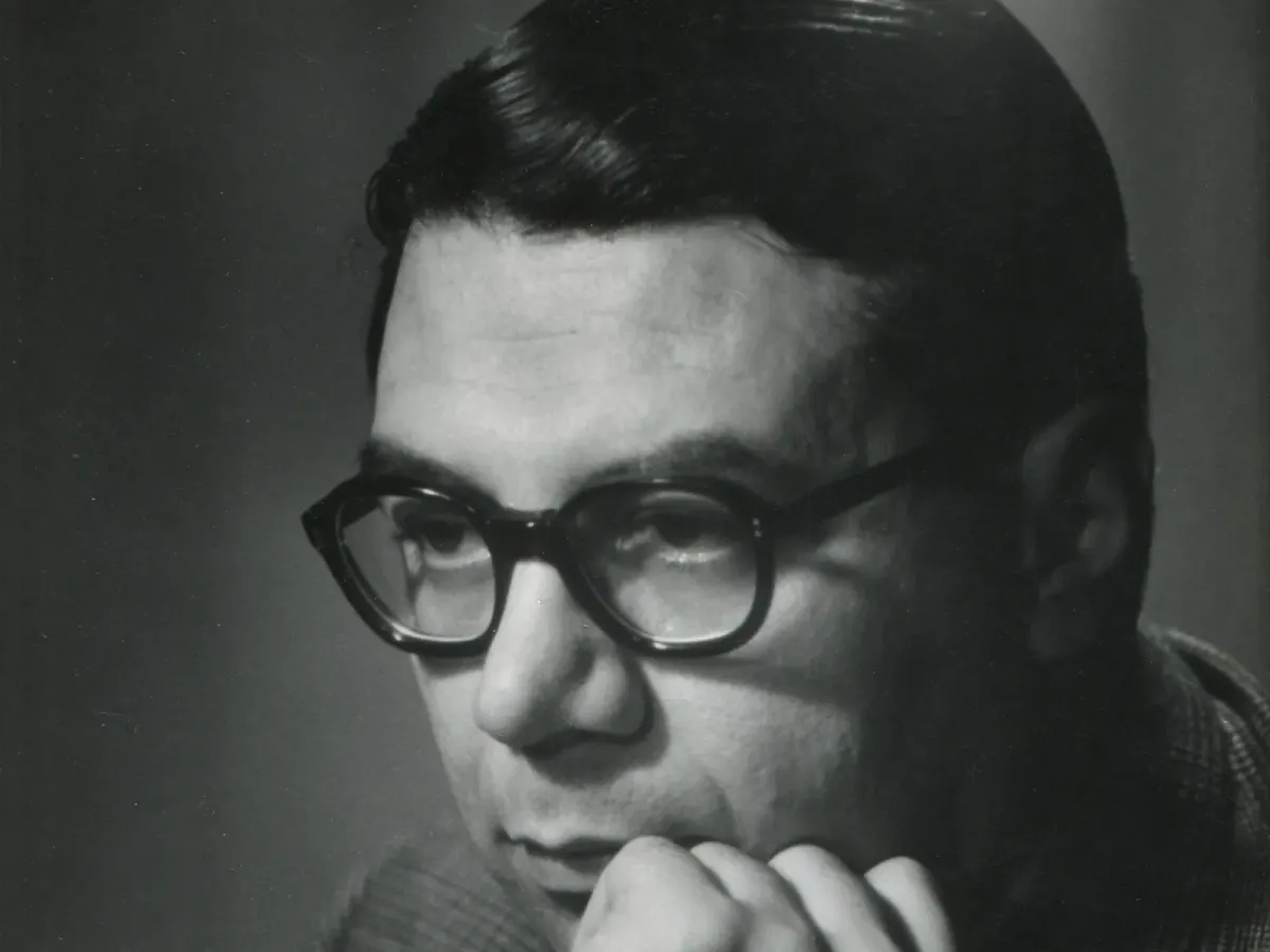 Retrato em preto e branco de Ariel Ramírez, compositor da Misa Criolla, de óculos de armação grossa e mão no queixo