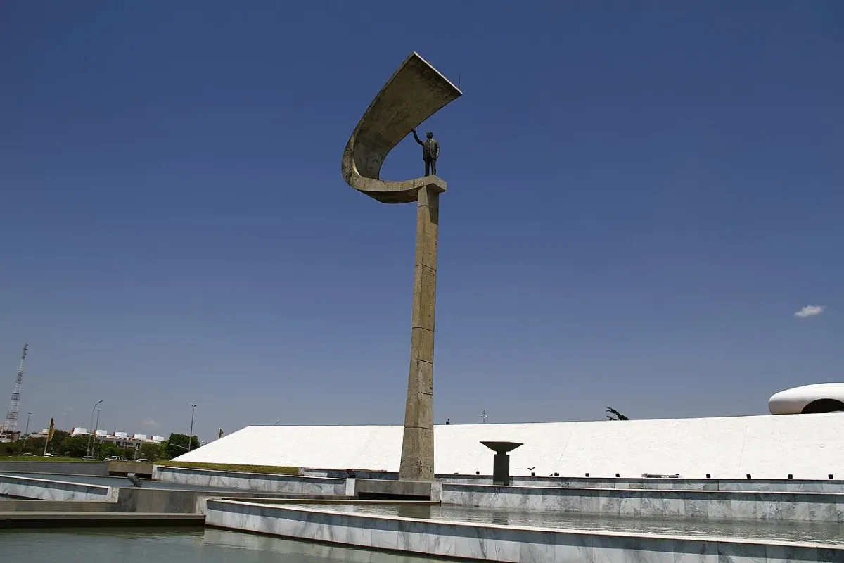 Memorial JK em Brasília, com a haste curva de concreto e a estátua de Juscelino Kubitschek sob céu azul