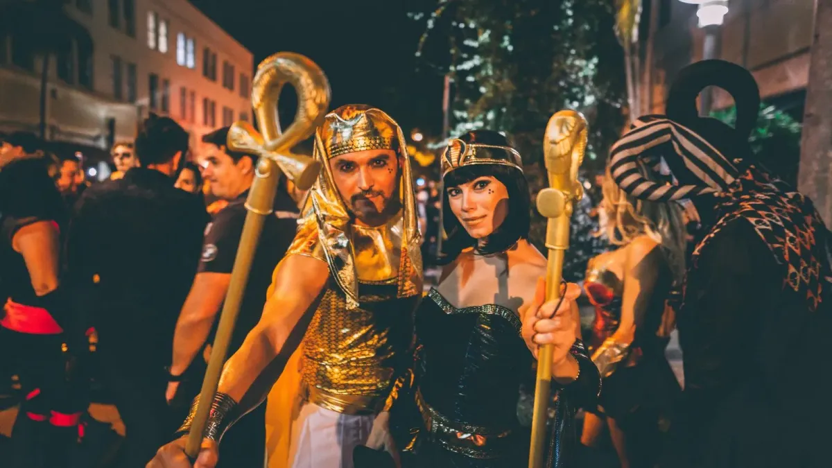 Casal fantasiado de faraó e Cleópatra em festa de rua à noite