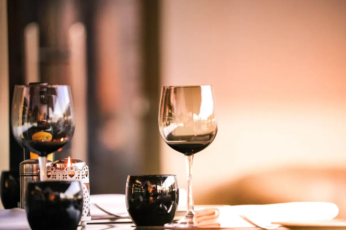 Duas taças de vinho tinto sobre mesa de restaurante, com vela acesa ao lado