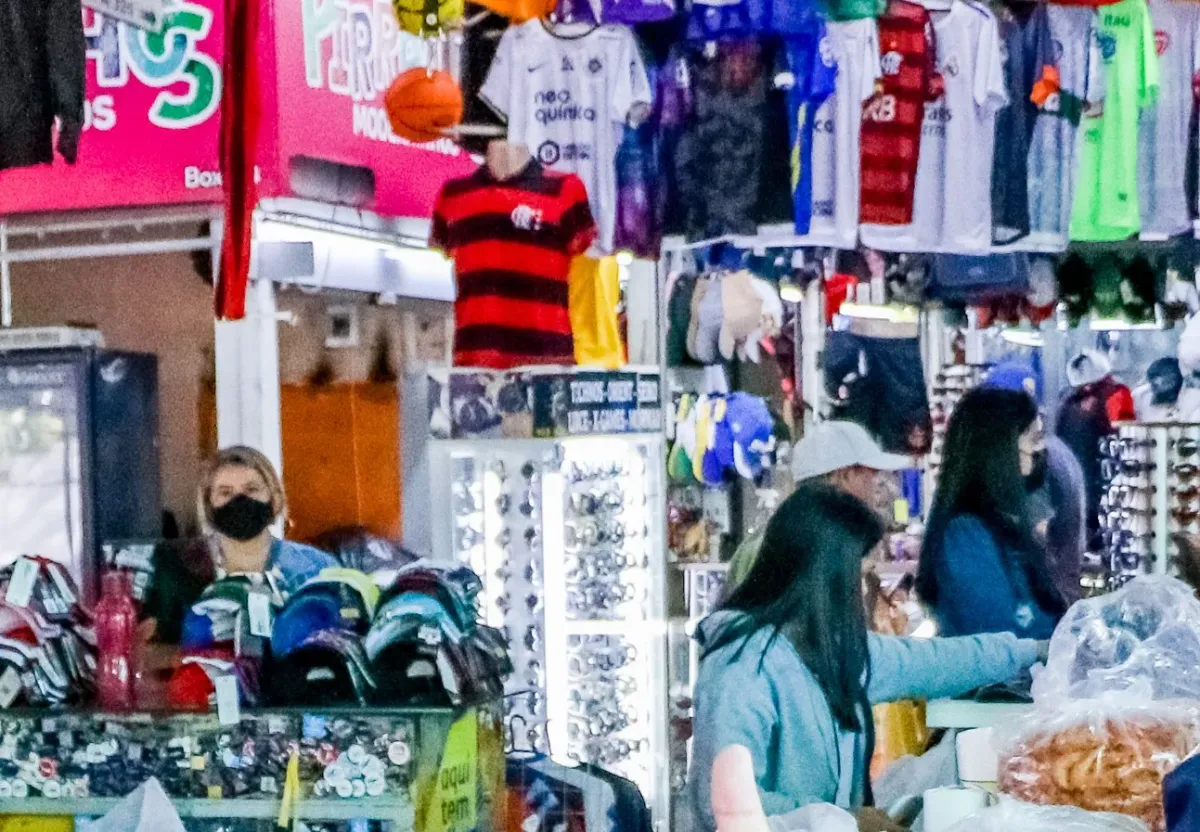 Estande de camisas de time e bonés em um corredor da Feira do Guará