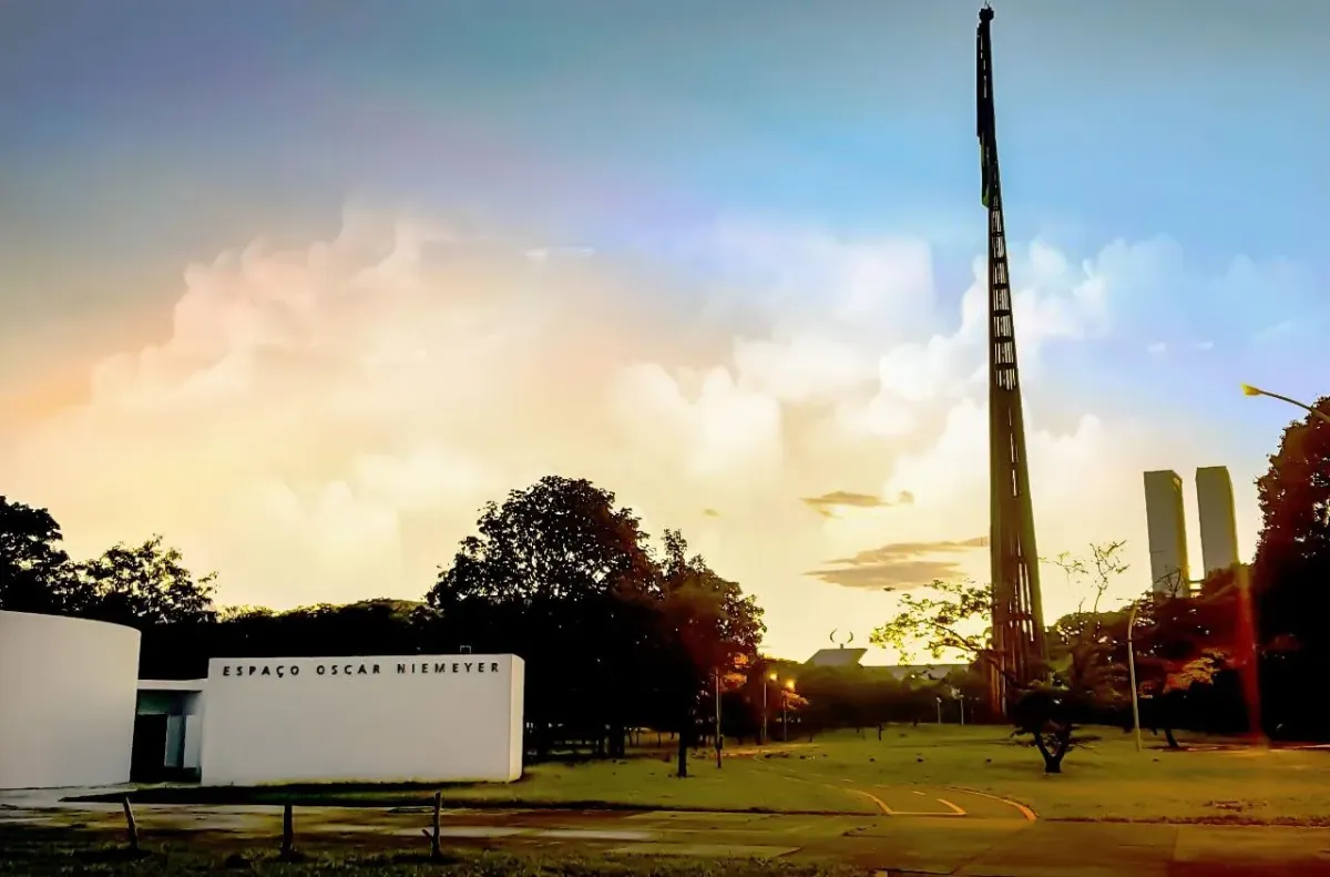 Fachada do Espaço Oscar Niemeyer, prédio branco com o nome na parede, ao lado do mastro da bandeira na Praça dos Três Poderes, em Brasília