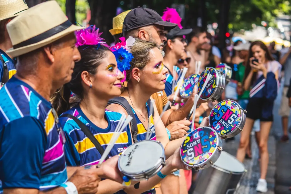 Mulheres tocam pandeiro em bloco de rua colorido