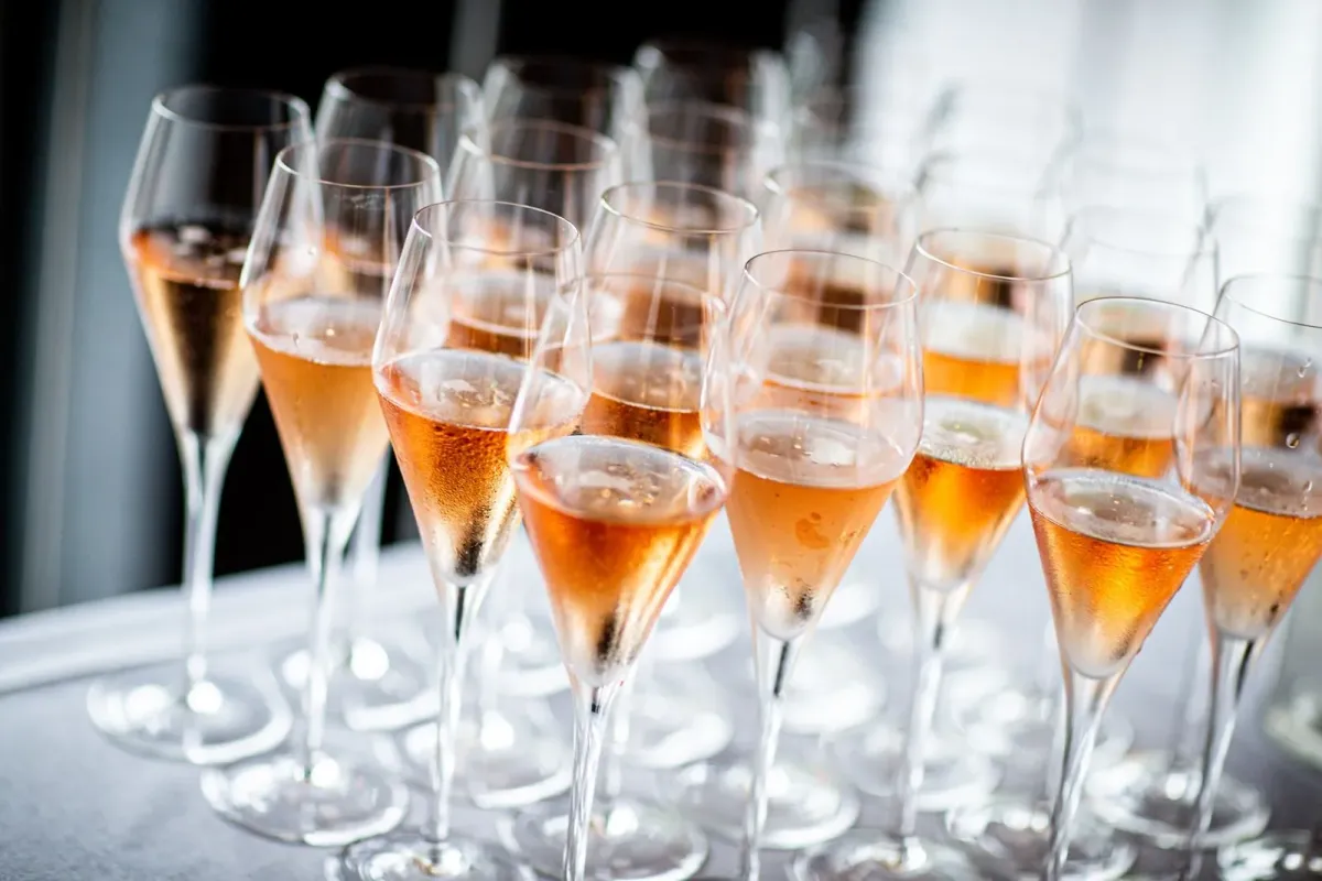 Taças de espumante rosé enfileiradas sobre uma mesa