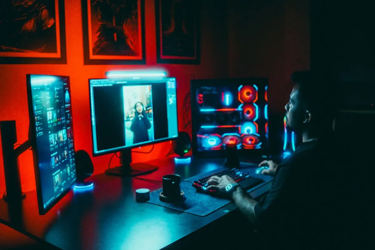 Desenvolvedor trabalha em estação de computador com três monitores e iluminação neon