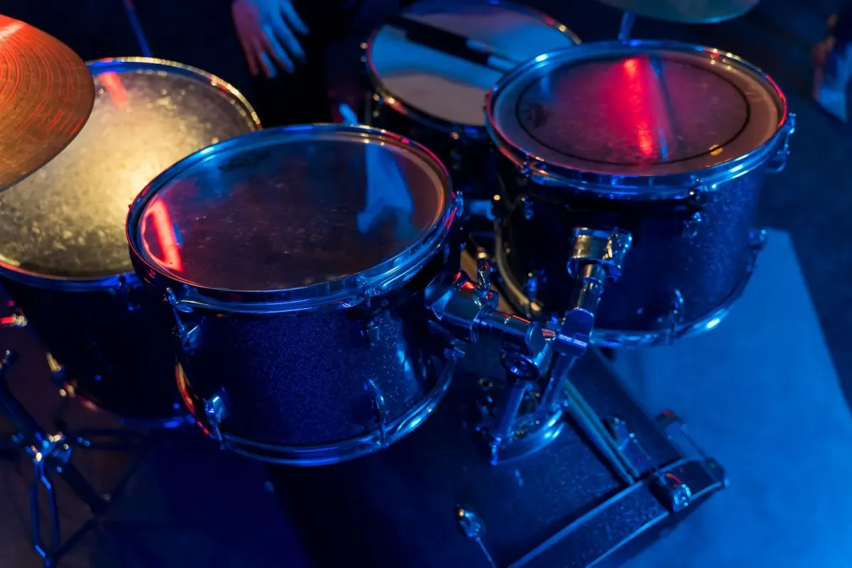 Bateria em palco com luzes azuis e vermelhas, foto ilustrativa de show de rock