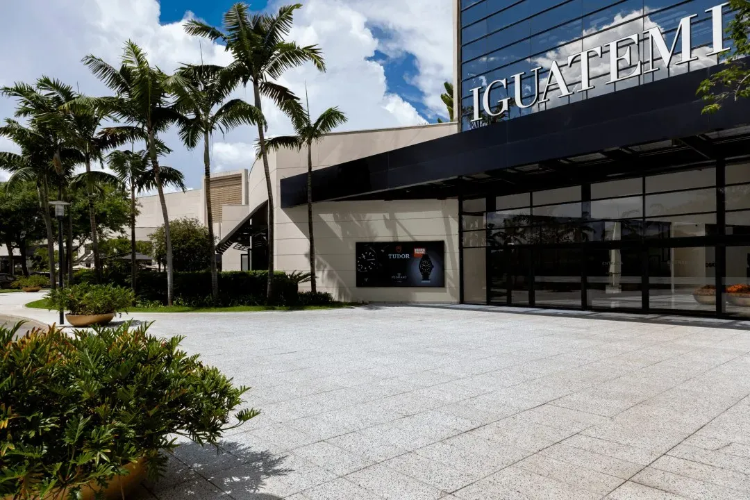 Fachada do Iguatemi Brasília com palmeiras e jardim numa praça de pedra sob céu azul